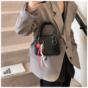 Close-up of black handbag with white contrast stitching and festive braided lucky charm