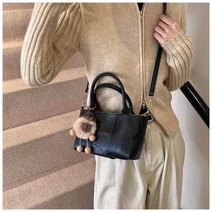 Détail du sac à main noir tressé avec bandoulière amovible et breloque lion en peluche