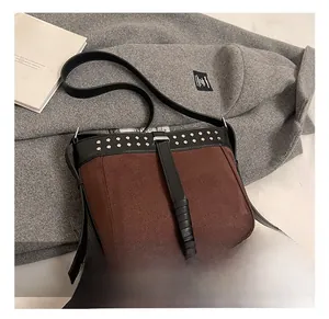 Detailed view of brown suede crossbody bag featuring silver studs and leather straps