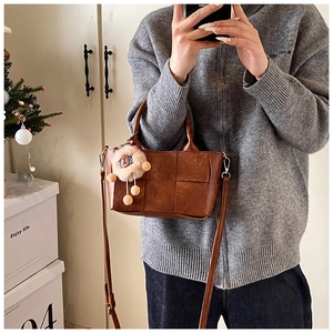 Sac seau tressé marron avec breloque lion dans un décor intérieur chaleureux