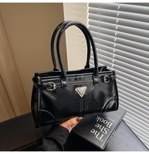 Detail of glossy black leather tote with silver triangle logo and metal buckles