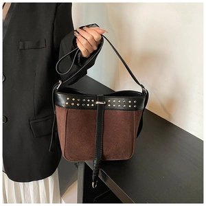 Detail of dark brown suede bucket bag with gold studs and black leather handle detail