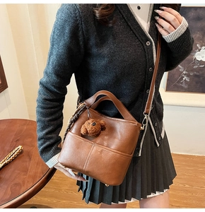 Close-up of retro brown bucket bag featuring fine leather texture and cute dog charm