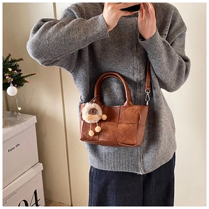Détail du sac seau marron tressé avec texture en cuir et accessoire de charme lion mignon