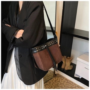 Detail of vintage brown suede messenger bag with black leather trim and silver rivets