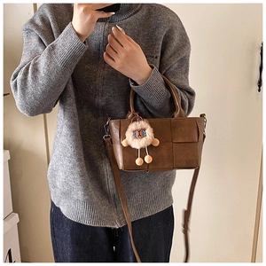 Détail du sac seau marron tressé avec bandoulière et pendentif en peluche rigolo