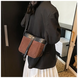 Detail of retro brown suede messenger bag with black leather straps and metal rivets