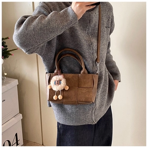 Sac seau tressé marron avec charme de mouton blanc et poignées dans un selfie miroir
