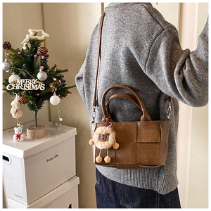 Détail d'un sac seau marron à texture tressée avec bandoulière et décor de fête