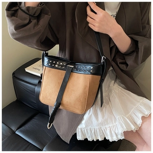 Brown suede and black leather crossbody bucket bag with silver studs on female model