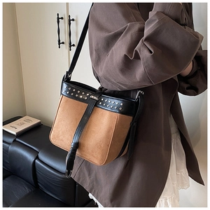 Detail of retro suede bucket bag with contrast stitching and metallic rivets decor