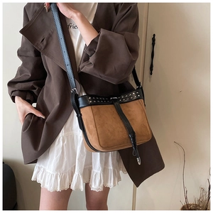 Brown suede crossbody bag with vintage rivets worn by a model in a brown blazer