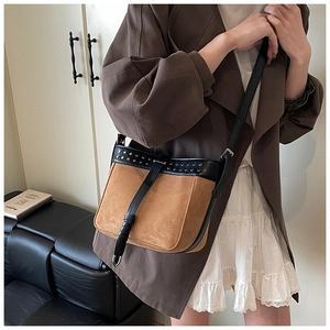 Detail view of retro crossbody bag with brown suede, black leather panels and silver rivets