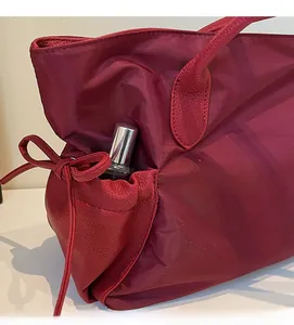 Détail du sac cabas en nylon rouge avec poche latérale à cordon et finitions en cuir