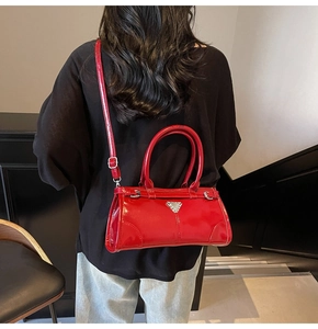 Back view of model wearing a glossy red patent leather crossbody bag with metal buckle