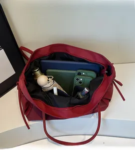 Vue de dessus de l'intérieur d'un grand sac cabas bordeaux avec essentiels de voyage
