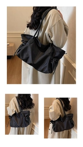 Détail d'un grand sac fourre-tout noir en nylon montrant sa texture légère et son cordon latéral