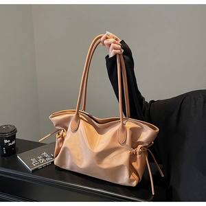 Gros plan sur un grand sac de voyage beige avec poignées en cuir et détails de cordon