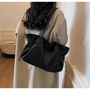 Détail du sac de voyage en nylon noir avec poignées en cuir et cordon pour femmes