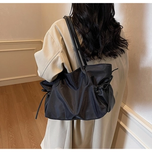 Détail du sac cabas en nylon noir avec cordon de serrage et design froncé sur le côté