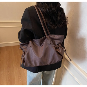 Détail du sac cabas en nylon marron foncé avec cordon de serrage latéral et garniture cuir