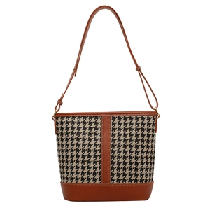 Houndstooth bucket bag with brown leather trim and adjustable strap on white background