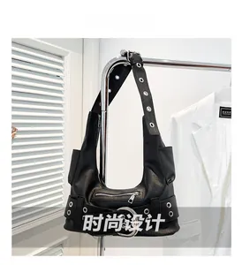 Detail view of black punk style shoulder bag with metallic eyelets and buckle accents