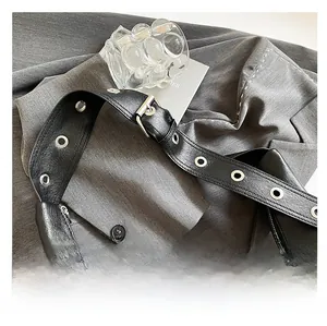 Macro detail of black leather shoulder bag strap with large silver metal eyelets