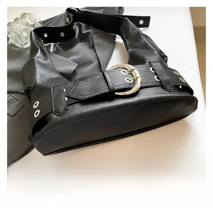 Detailed close-up of punk style black underarm bag with oversized silver metal buckle