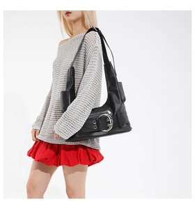 Detail of black punk shoulder bag with silver grommets and wide strap on model