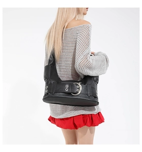 Detail of black faux leather shoulder bag with oversized silver buckle and punk aesthetic