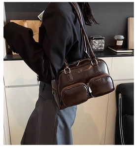 Detail view of a vintage dark brown shoulder bag with dual zipper front pockets