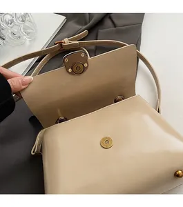 Detail of magnetic snap closure on cream leather tote with adjustable shoulder strap
