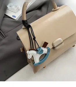 Detail of a chic wooden horse leather charm attached to a beige crossbody tote bag