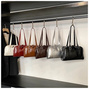 Detail view of retro faux leather tote bags in six colors hanging on a metal bar