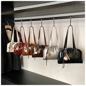 Row of vintage bowling bags in six colors with mini baseball charms on a boutique rack