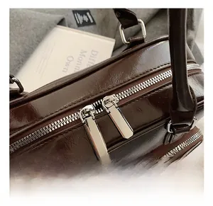 Detailed close-up of dark brown glossy leather handbag with silver dual zipper pulls
