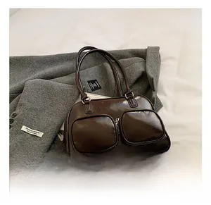 Detail of dark brown glossy underarm bag featuring double front zip pockets and silver hardware
