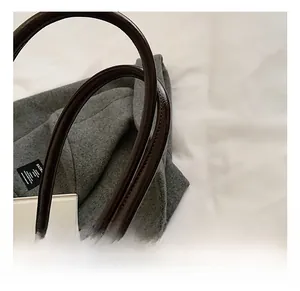 Detail showing the comfortable leather handle and fine stitching on a tweed handbag