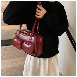 Detail of vintage burgundy glossy leather shoulder bag with two front zipper pockets