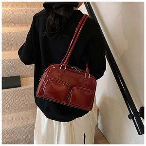 Detail of burgundy glossy underarm bag with double front zip pockets and silver hardware