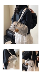 Close-up of silver metallic bowling bag featuring vintage straps and baseball charms