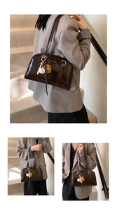 Detail view of dark brown gloss shoulder bag with baseball charms on a minimalist stair