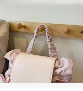 Detail van lichtroze rugzak met geplooide handgreep aan houten haak minimalistisch