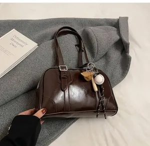 Close-up view of dark brown underarm shoulder bag with creative baseball charm set