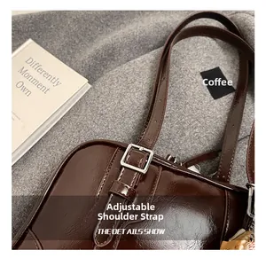 Détail de la bandoulière en cuir réglable et de la boucle en métal argenté sur un sac marron
