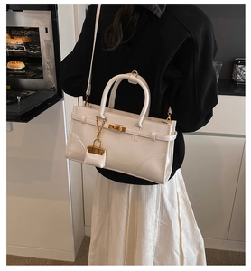 White faux leather crossbody bag with gold lock buckle shown in a kitchen setting