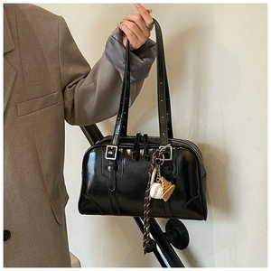 Detail of black patent leather tote bag with silver buckle and cute character charms