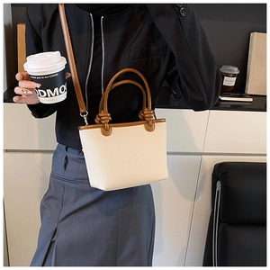 Détails du tissage crème et de la poignée en cuir marron noué d'un petit sac bandoulière
