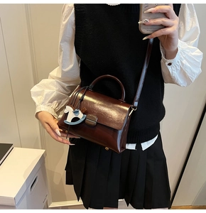 Close-up of brown vintage crossbody bag with square metal buckle and a blue wooden horse charm